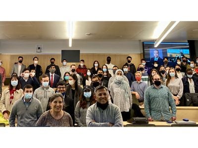 students standing up in a full lecture hall.