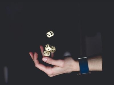Image of a man's hand throwing dice in the air.