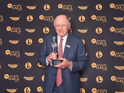 George Gellert in front of a background holding his award