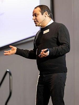 A man speaking on stage and gesturing.