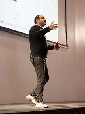 A man speaking on stage and gesturing.