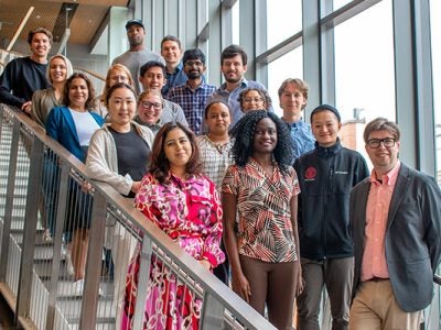 A group of 18 students poses on the stairs at the Breazzano Center.