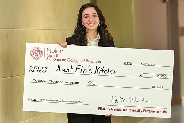 Armita Jamshidi &rsquo;25 holding a novelty check for $25,000 made out to Aunt Flo