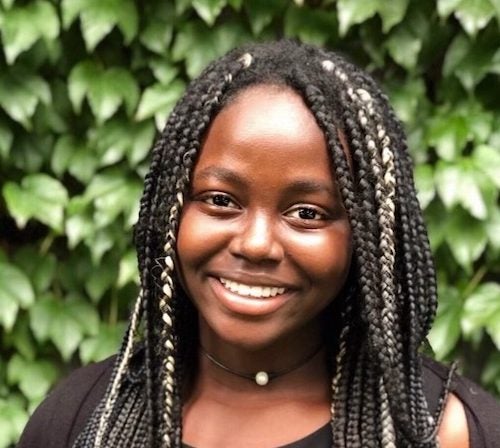 Jenniviv Bansah smiles in front of greenery.