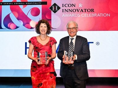 a woman and a man standing next to each other, holding crystal awards and smiling.