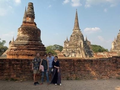 Four students stand in front of a large temple in Thailand