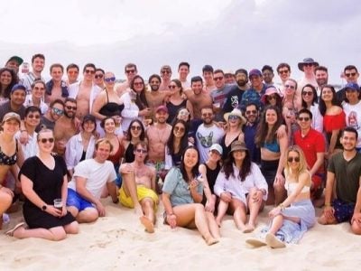 a large group of young adults on a sandy beach.