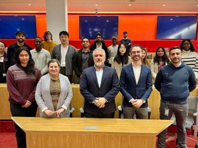 Lourdes Casanova, Ivan Duque and 16 students standing in a lecture hall, smiling and looking at the camera.