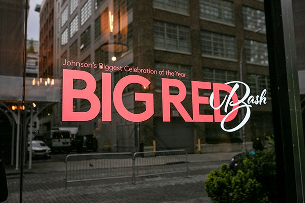 A "Big Red Bash" sign on the window of a building, reflecting another building across the street.