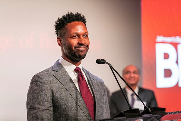 A man standing in front of a microphone and smiling.