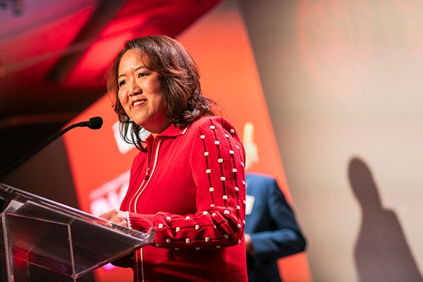 a woman speaking into a microphone and smiling.