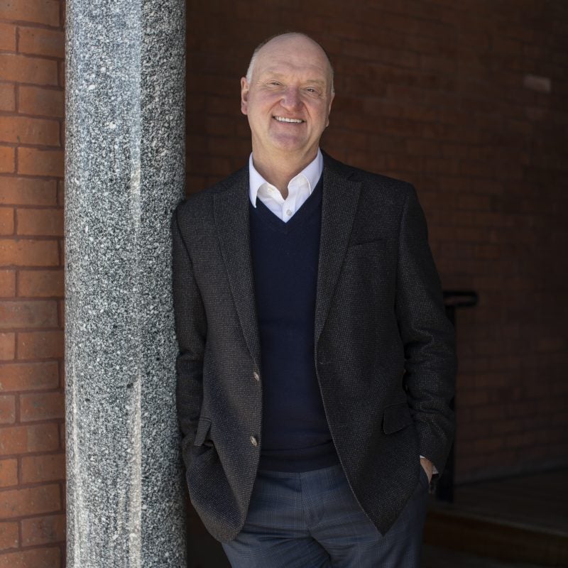 Dean Andrew Karolyi leans against a pillar outside of Sage Hall.