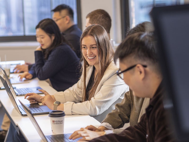 Student smiling, working with other student in class