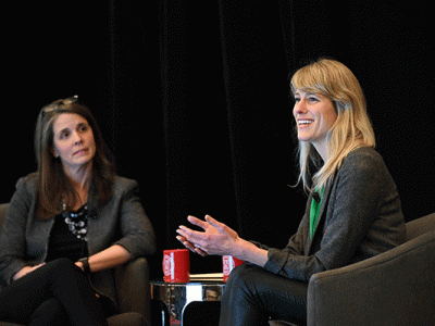 Laura Georgianna and Jessica Rolph sit facing each other in chairs on stage., Jessica is speaking.