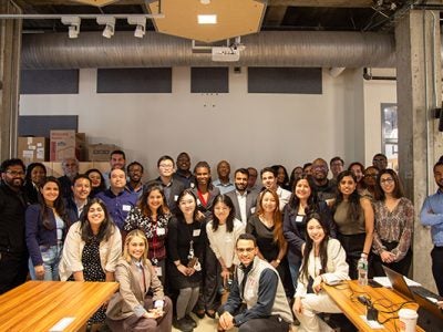 Members from all 28 teams pose for a group photo in business casual attire.