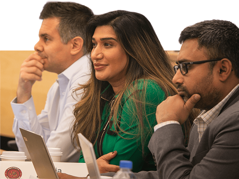Three Executive MBA Americas students in a class setting.