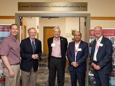 5 men standing side by side, smiling, at the entrance of a suite with a sign over the entrance that reads: L. Joseph Thomas Diversity, Inclusion, and Leadership Suite.
