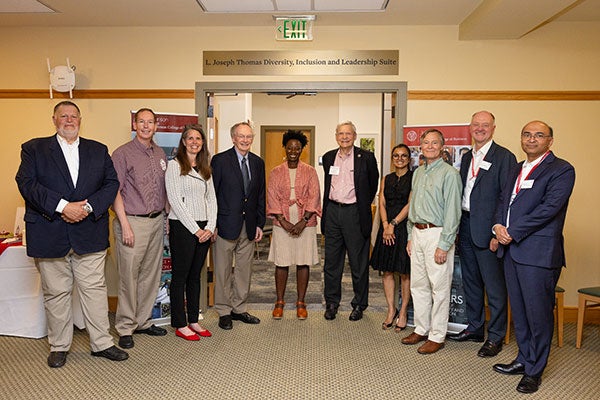 7 men and 3 women standing side by side in front of the entrance to the L. Joseph Thomas Diversity, Inclusion, and Leadership Suite.