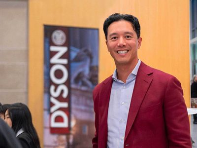 John Wu standing next to a Dyson School banner.
