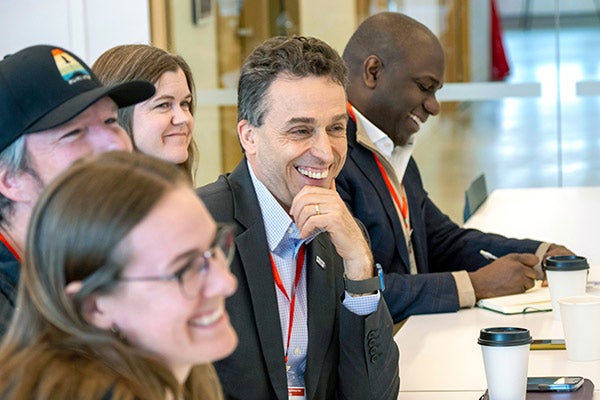 Judges sitting at a conference table in the front row and smiling as they interact with presenters.