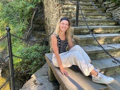 Kyra Stiggelbout sitting on a stone step wearing New Balance sneakers.