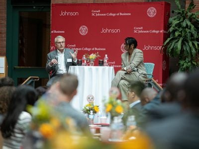 Larry Ruff and Cynthia Saunders-Cheatham seated on a stage and speaking to a room full of people