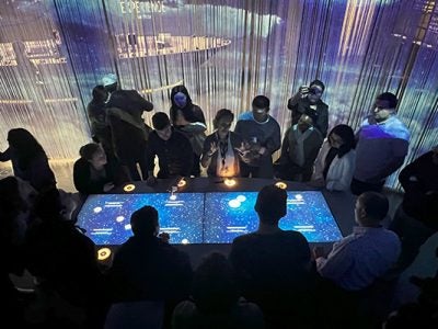 people gathered around a table lit up with large video screen display.