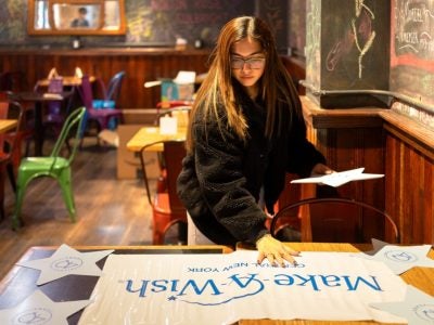 Image of female student setting up for a “Paint and Sip” event at Collegetown Bagels in Ithaca, to raise money for Make-A-Wish Central New York.