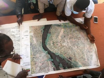 A group of people crowd around at a map with a river, the photo is taken from above.