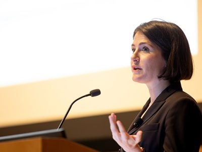 a headshot of Maxine Bédat speaking into a microphone.