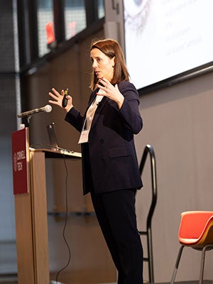 A woman speaking on stage and gesturing.
