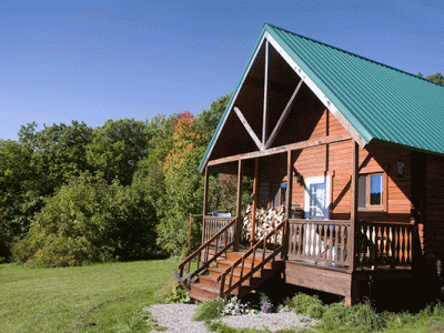 Photo of a cabin in a field with trees in the back