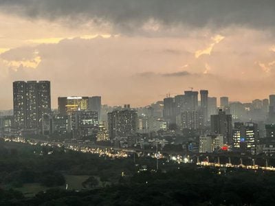 photo of a large city filled with tall buildings and a busy highway, taken in the evening and showing lights in the buildings and traffic-filled highway.