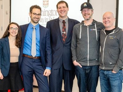 One female and two male students dressed in business attire with two older men dressed in zip-up hoodies with the Flickr logo.