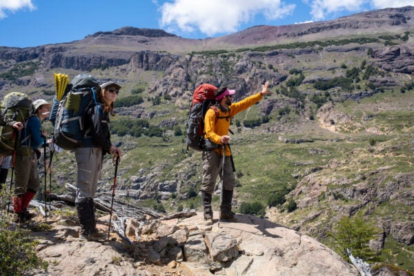 Cornell MBA students walk and point in hiking gear within a Patagonian mountain setting as part of an expedition