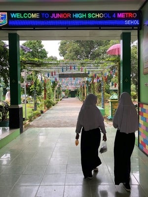 School entrance and walkway with two girls walking away under a sign that reads, &ldquo;Welcome to Junior High School&rdquo;