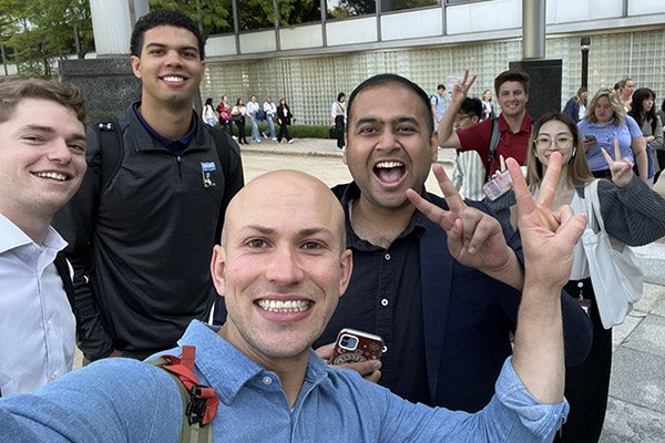 Ian Cairns and a group of interns smiling and giving the peace sign.