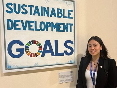 Rafaela Baldeón standing next to a large framed posted with the words "Sustainable Development Goals."