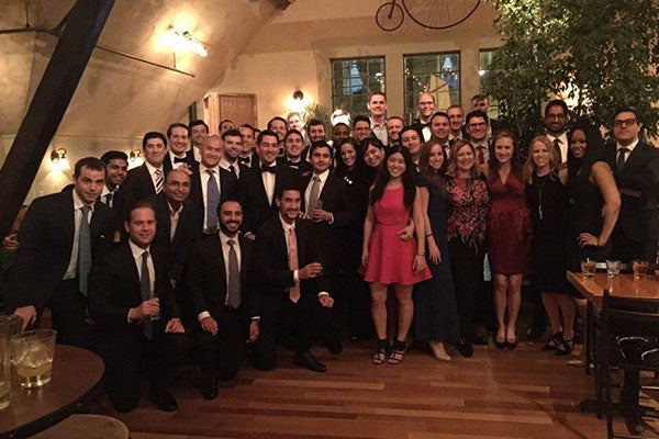 A large group of students dressed in business attire posing for a photo at one end of a large room.