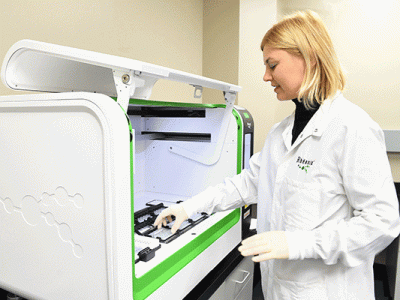 A scientist loads a Rheonix CARD cartridge onto the Encompass MDx workstation