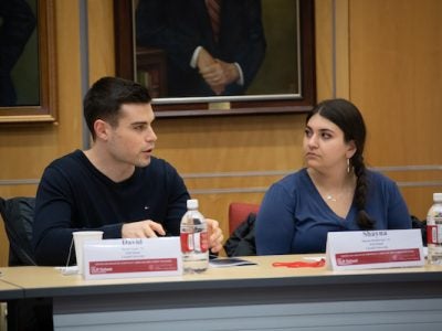 A male and a female student sit behind a table.