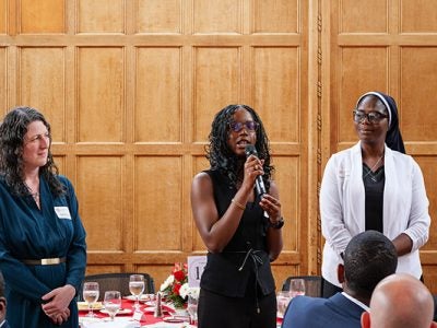 Professor Daniella Scur, Nneoma, and Rev. Sr. Matilda Adeboye of Louisville Girls High School in Nigeria, standing at the front of the room speaking at the Merrill Presidential Scholar luncheon.
