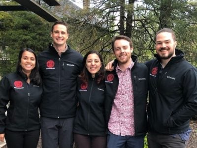 Five students pose for a photo wearing branded jackets.