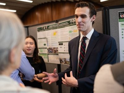 A student presents his project, CarbonWatch, to a symposium attendee.