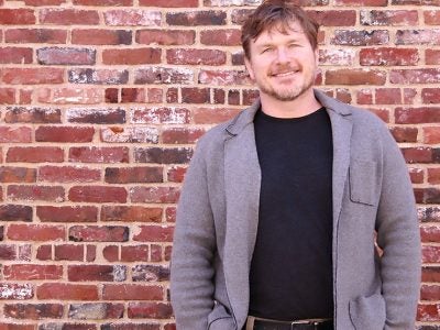 portrait of Scott Yewell standing in front of a brick wall