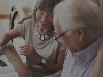 photo of an elderly couple sitting next to each other and looking at a photo album.
