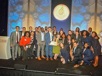 Photo of Consortium members standing on stage with a trophy