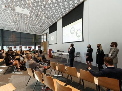 Students dressed in professional attire addressing a lecture hall audience