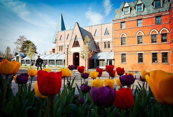 Photo of Sage Hall, with red and yellow tulips in the foreground.
