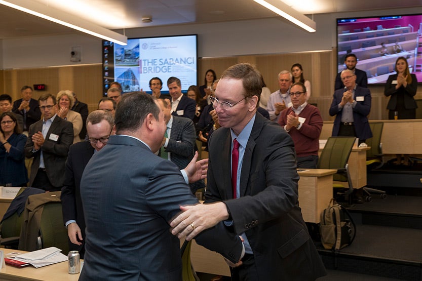 Dean Mark Nelson shaking hands with Demir Sabanci, MBA &rsquo;99, at the Sabanci Bridge dedication, Oct. 21, 2019. Members of the Johnson Advisory Council are seated in the background.